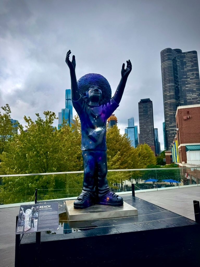'Reach' sculpture of a child reaching skyward against a city skyline